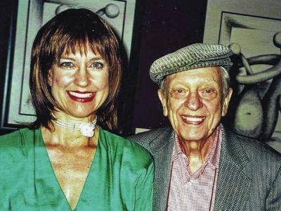 Karen Knotts is wearing a green dress and Don Knotts is wearing a grey suit and a cap.